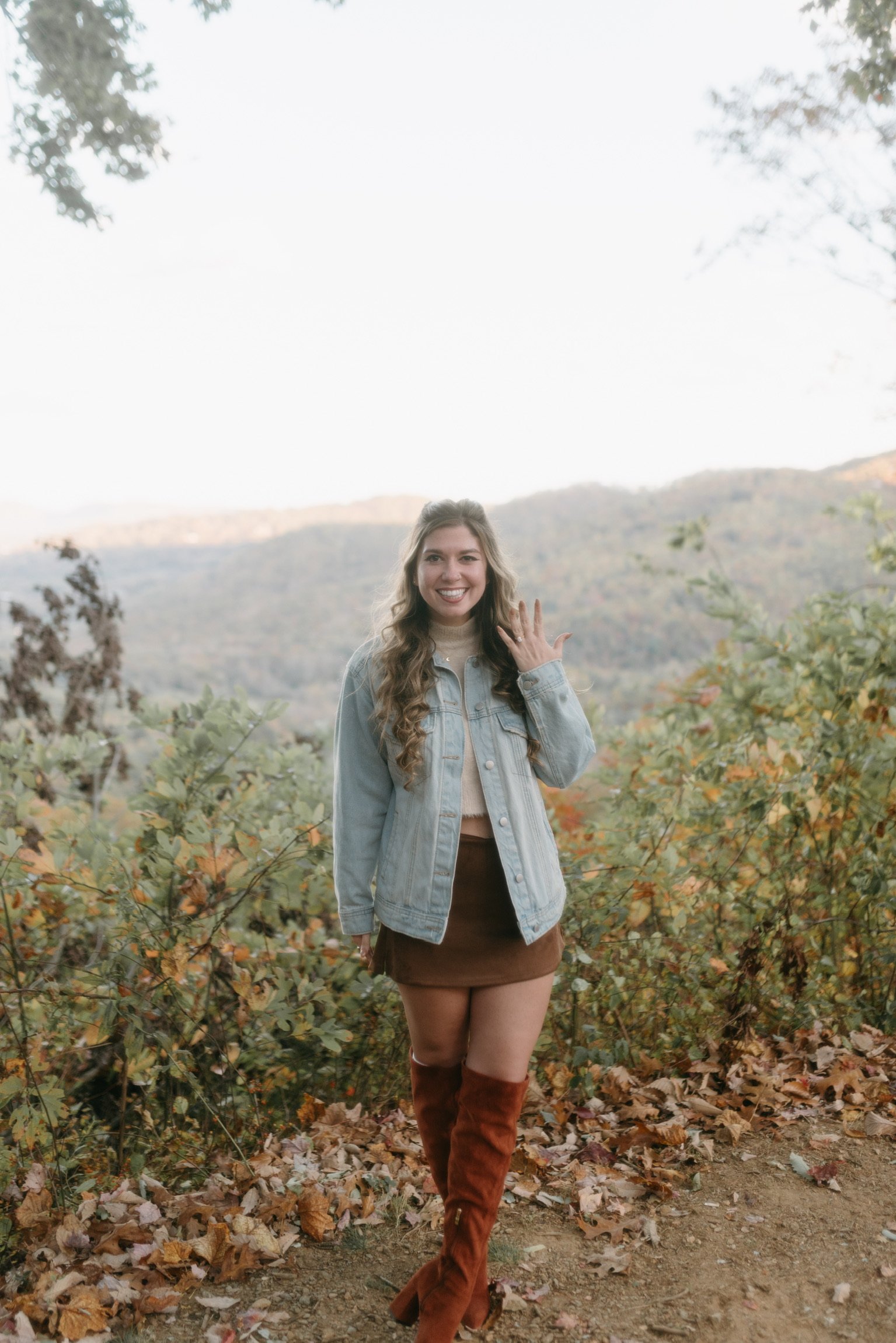 Nicole alone at the overlook, smiling and holding up her ring hand.