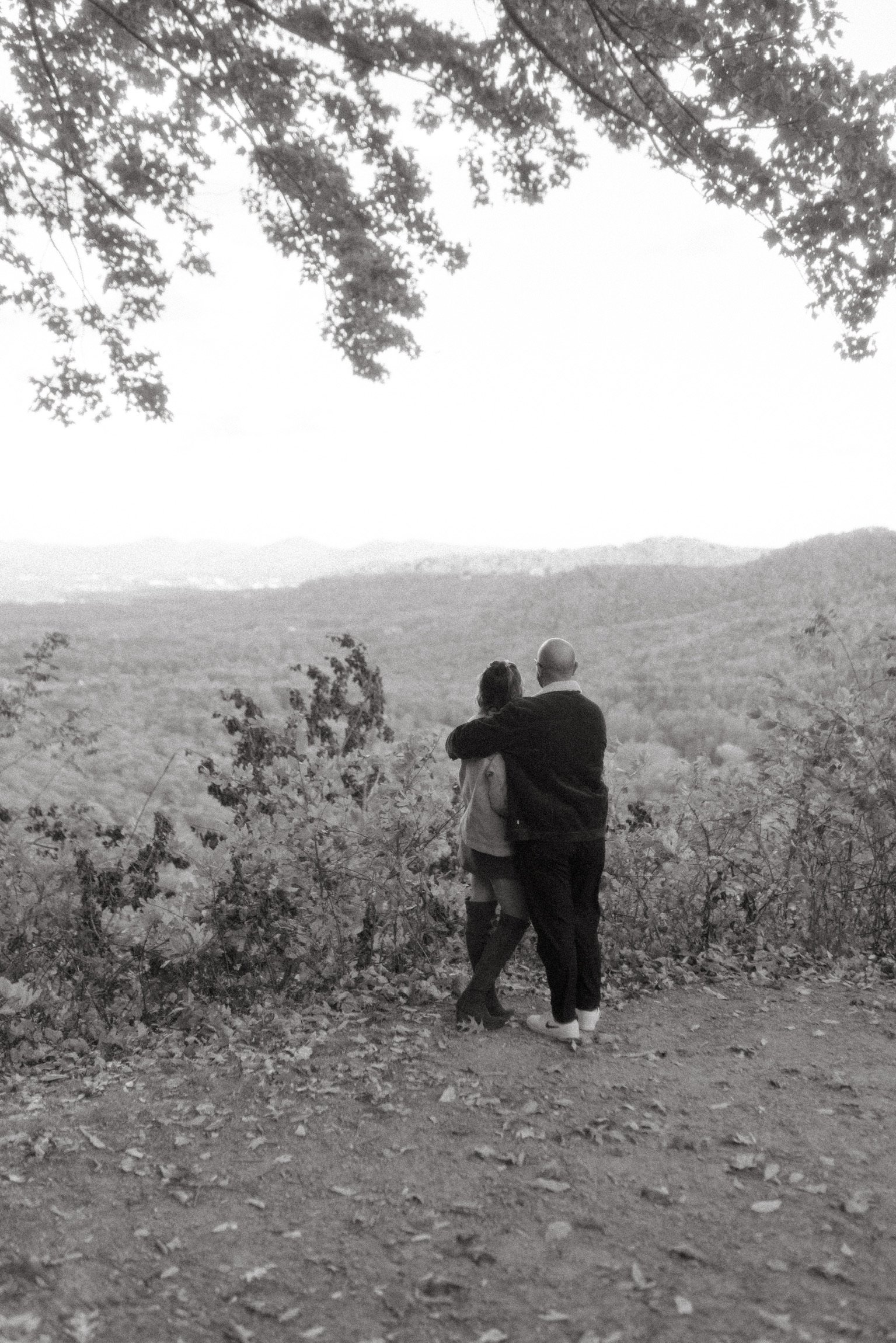 In black and white, from behind: the two of them holding each other, looking out over the valley.