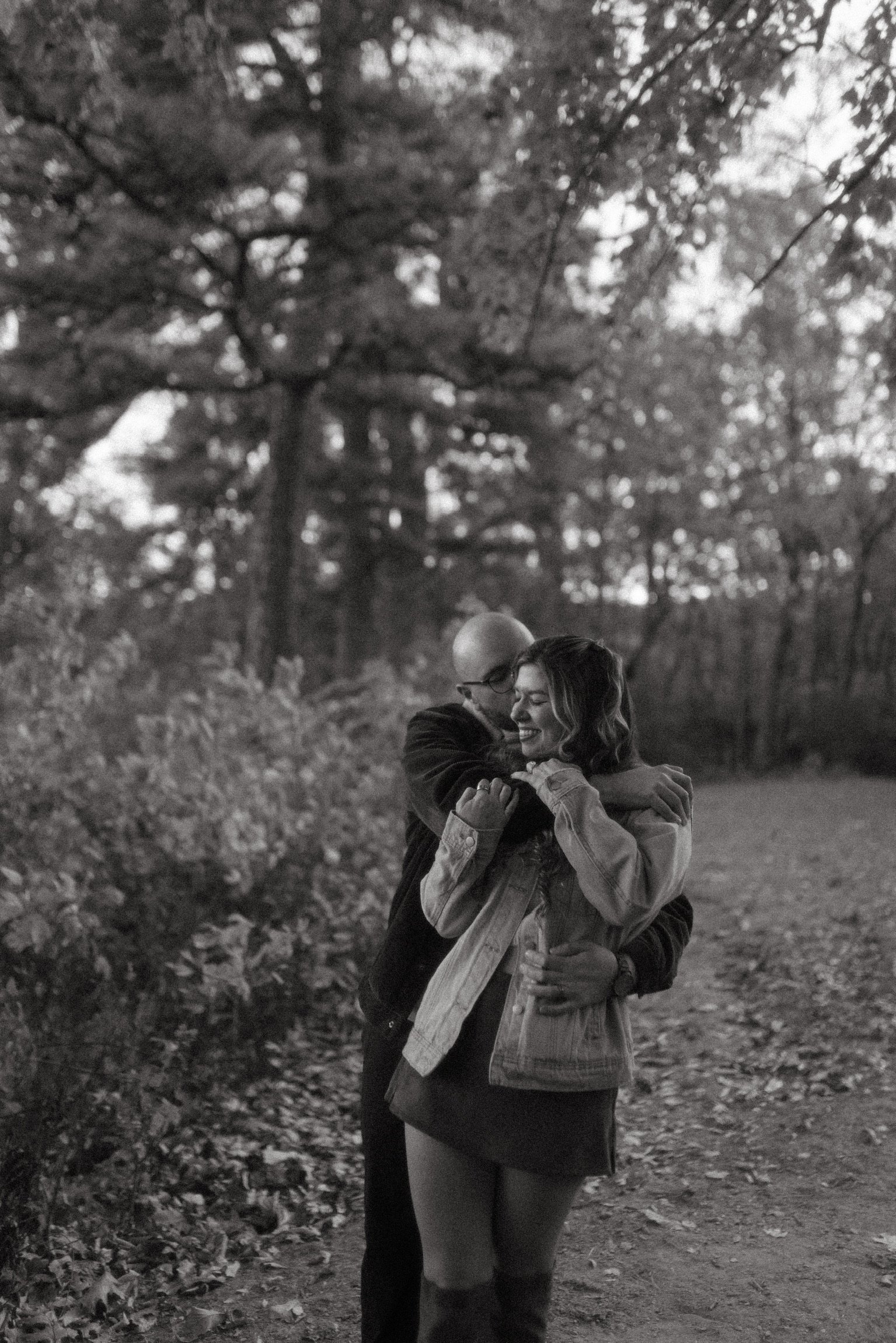 In black and white: Nicole leaning back into Ian’s arms on the woodland path.
