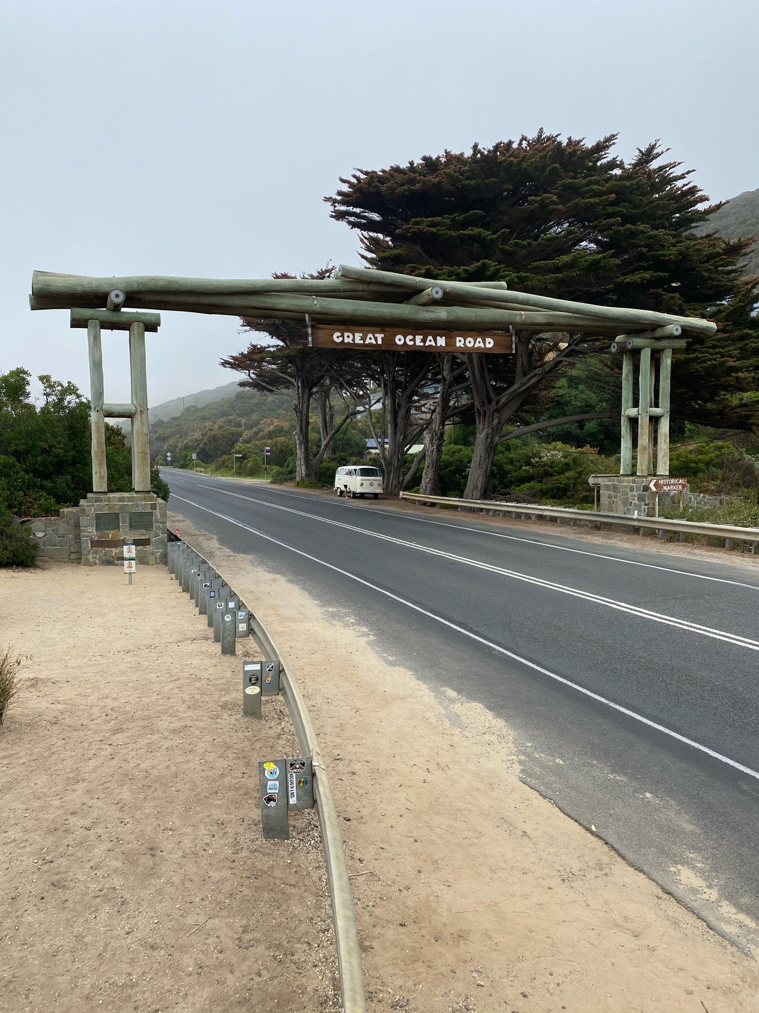 The Great Ocean Road memorial arch, a timber gateway over the road beneath cypress trees.