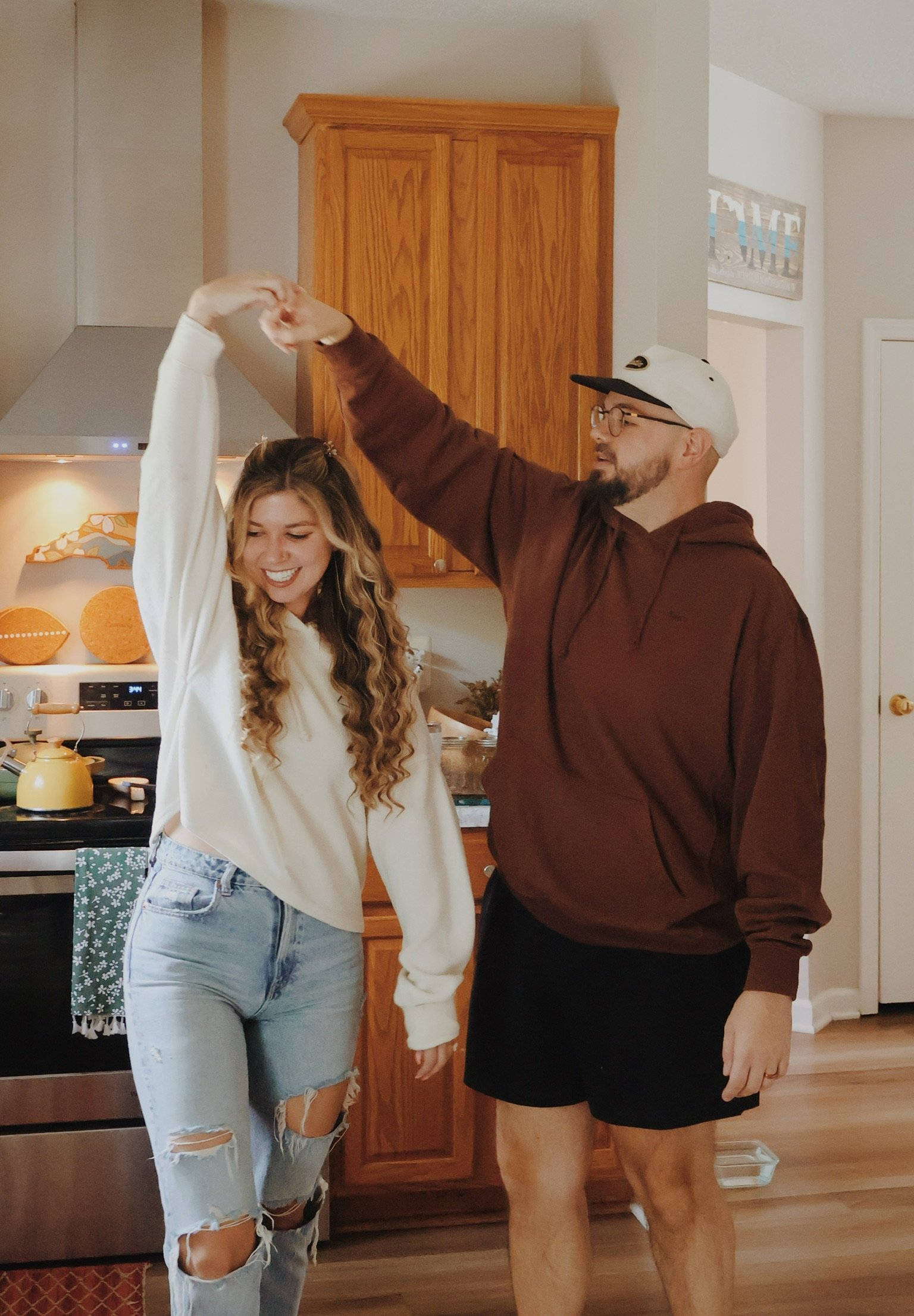 Ian spinning Nicole under his arm in the kitchen, both laughing.