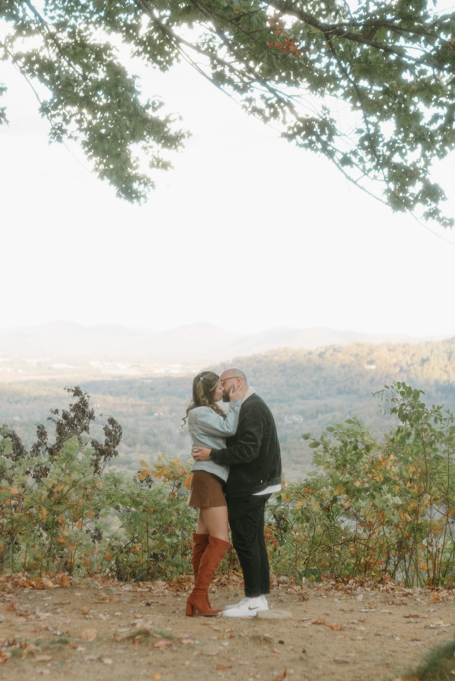 The two of them kissing under the overhanging branches, the valley behind.