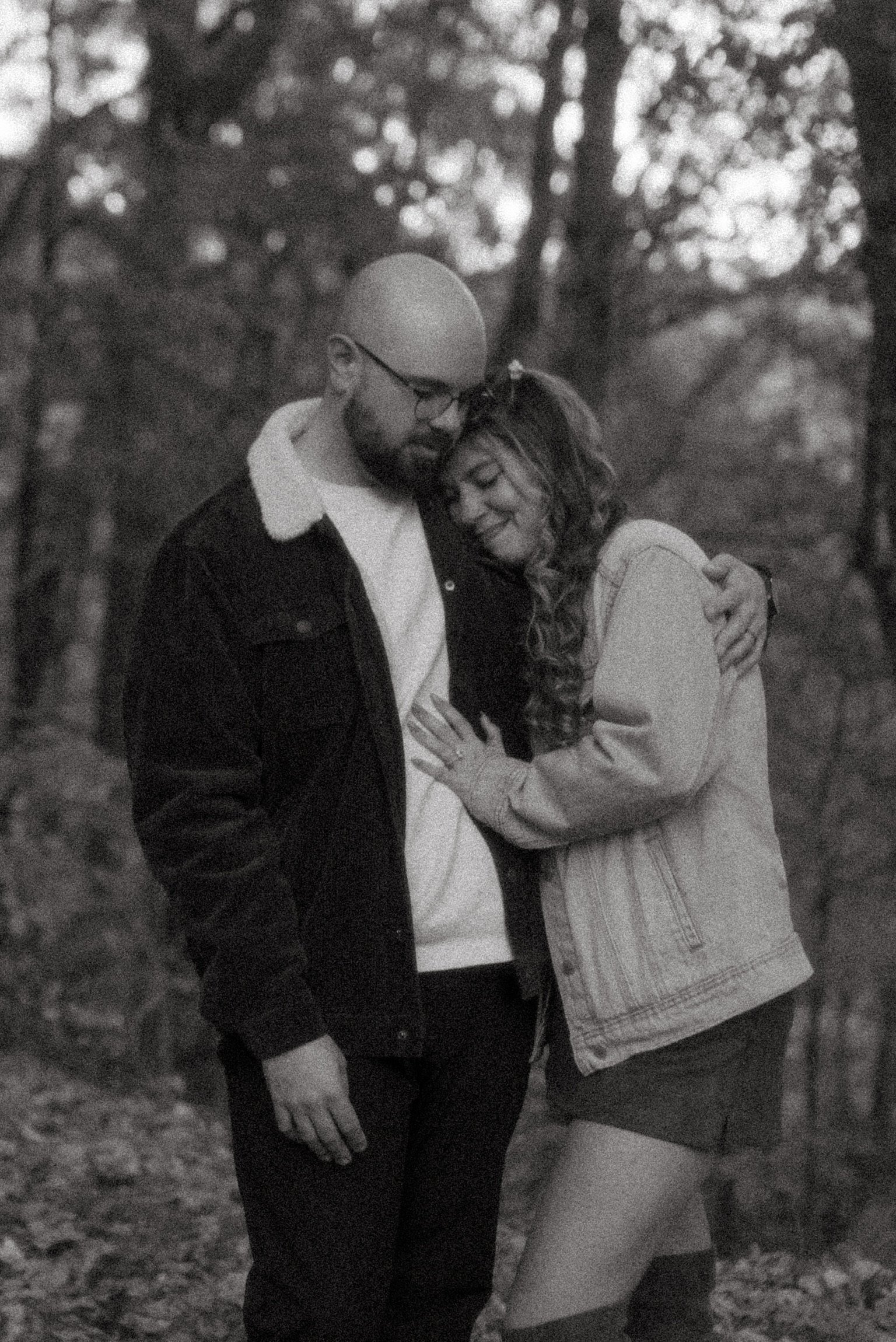 In black and white: Nicole resting her head on Ian’s chest in the woods.
