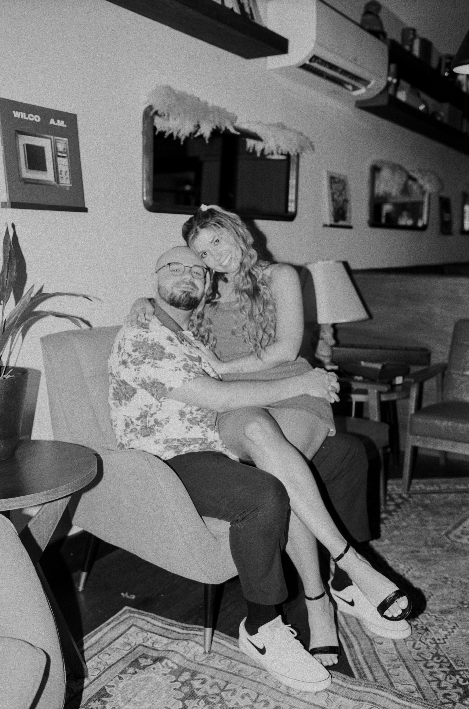 In black and white: Nicole sitting on Ian’s lap in the armchair, head on his shoulder.