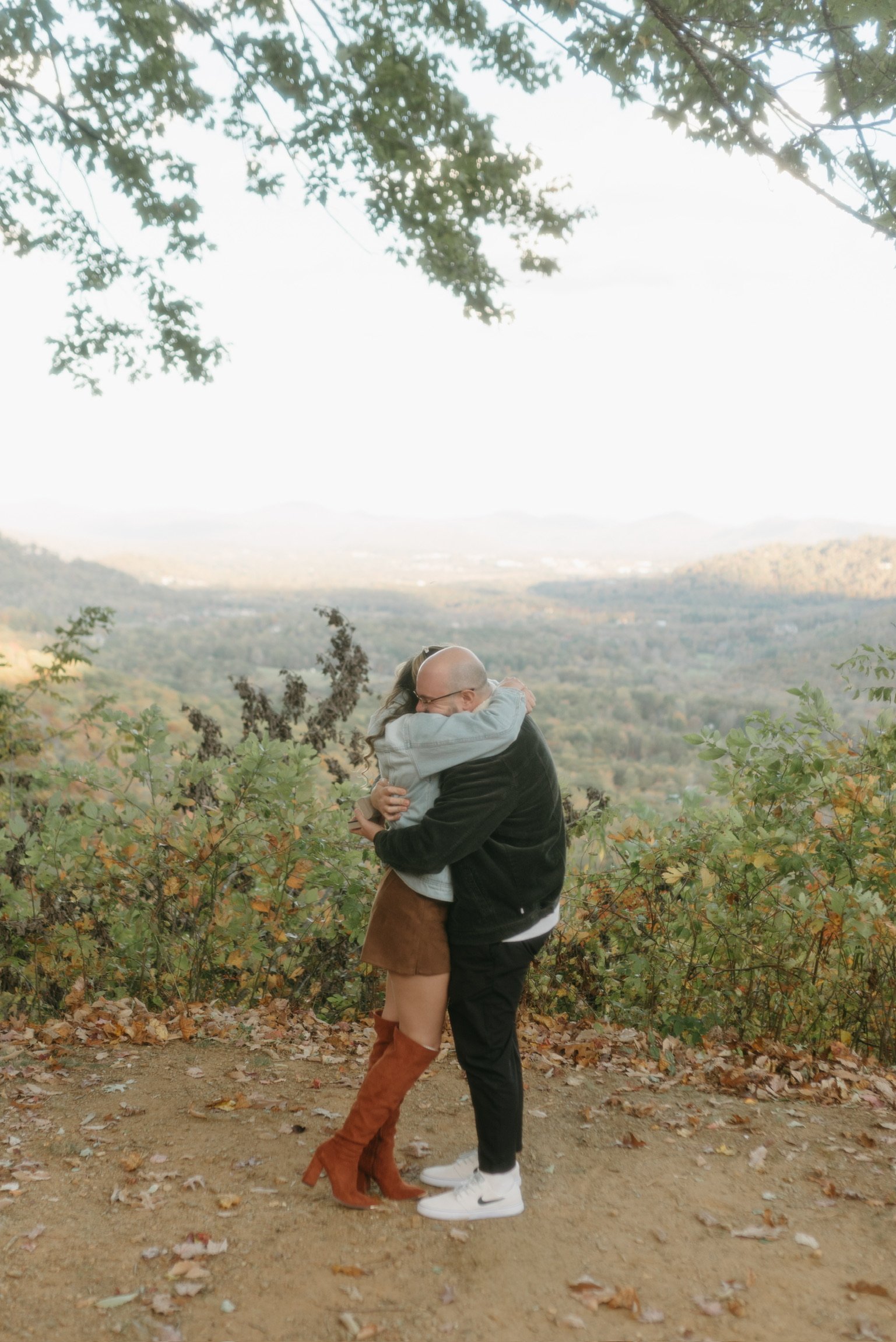 Nicole throwing her arms around Ian at the overlook, the mountains below.