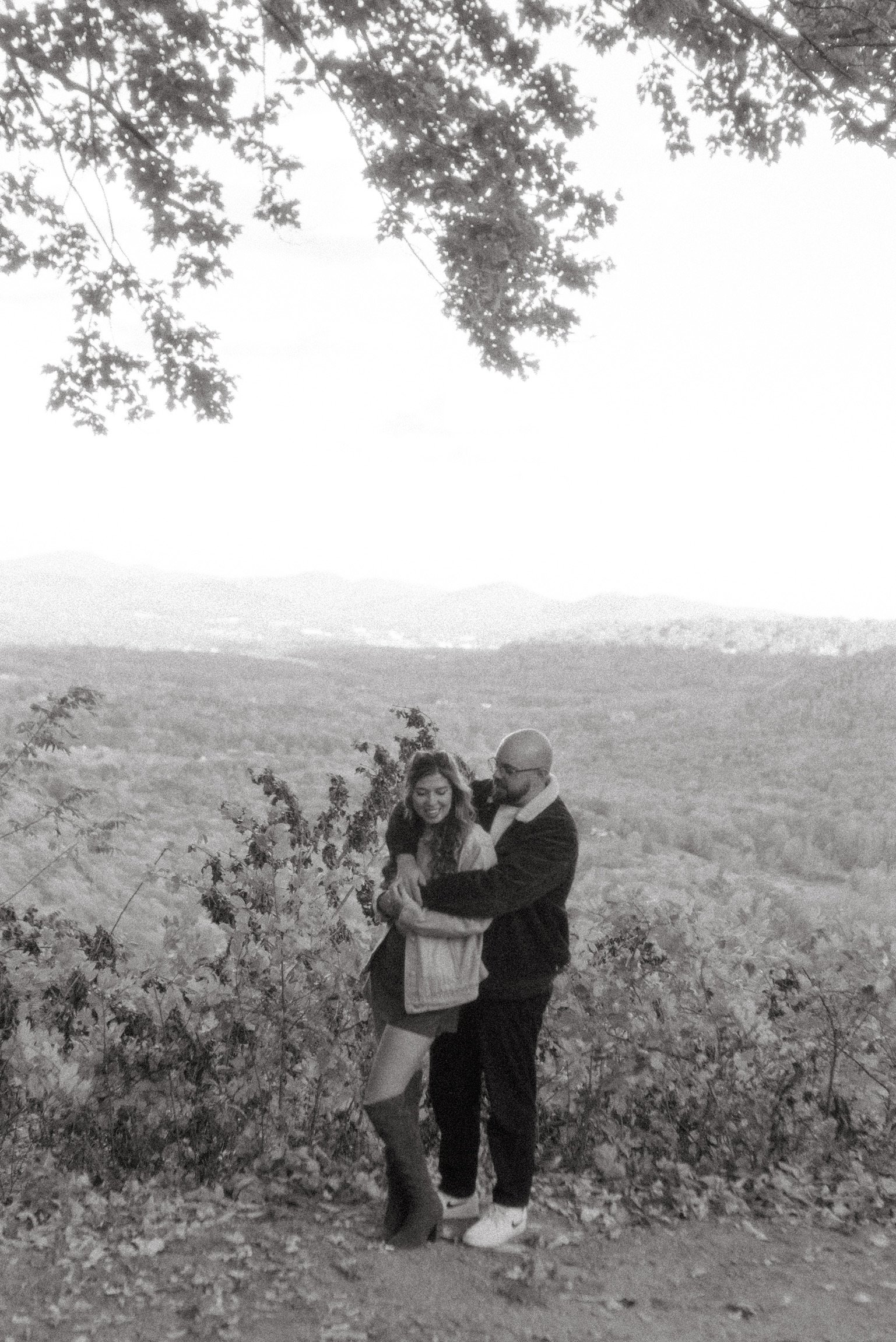 In black and white: the two of them embracing at the overlook edge.