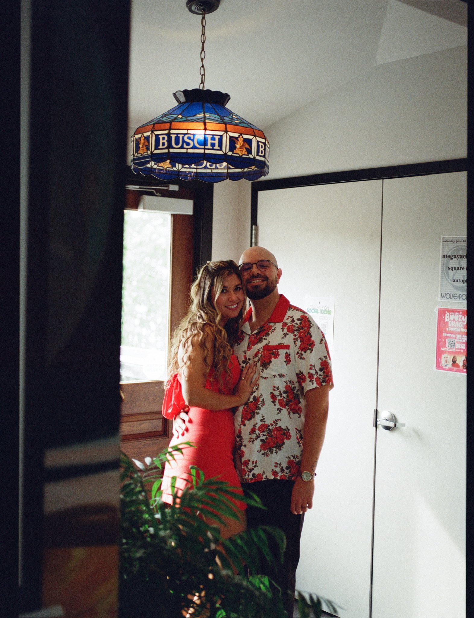 Nicole and Ian standing in a doorway beneath a stained-glass Busch lamp.