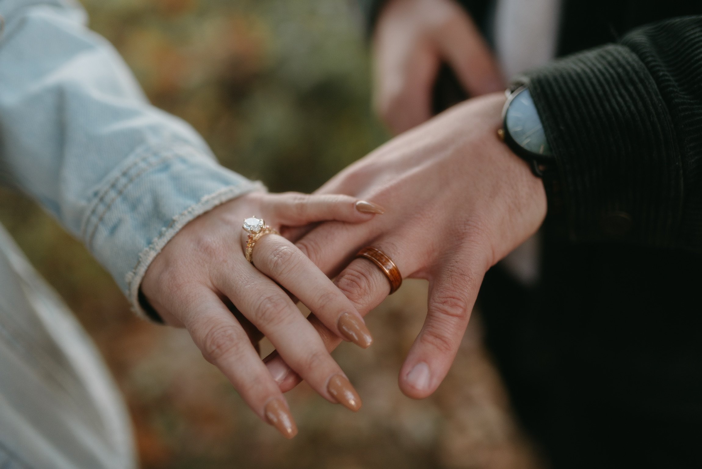 Close up: Nicole’s ringed hand resting on Ian’s, his watch at the edge of the frame.