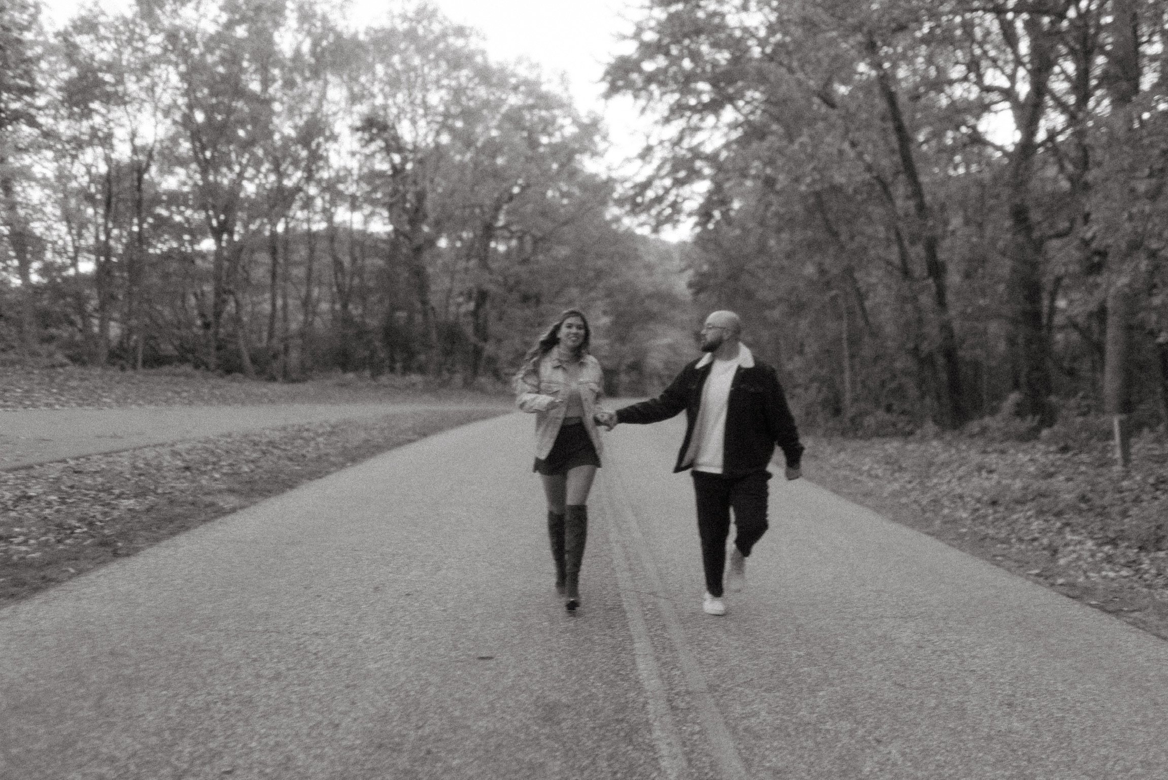 In black and white: Nicole and Ian walking toward the camera down the middle of the empty road.