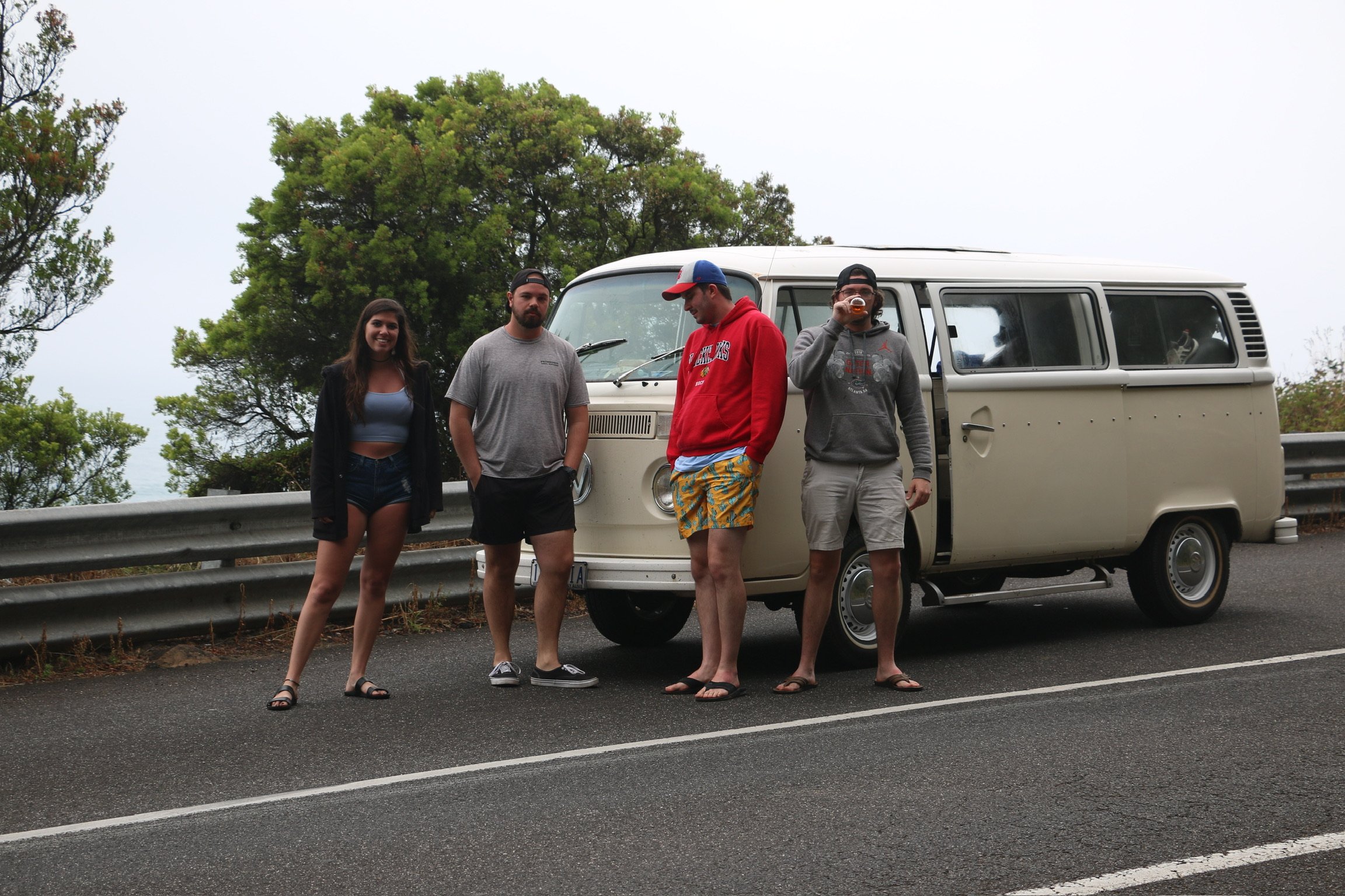 Four friends standing at the roadside in front of the cream kombi.
