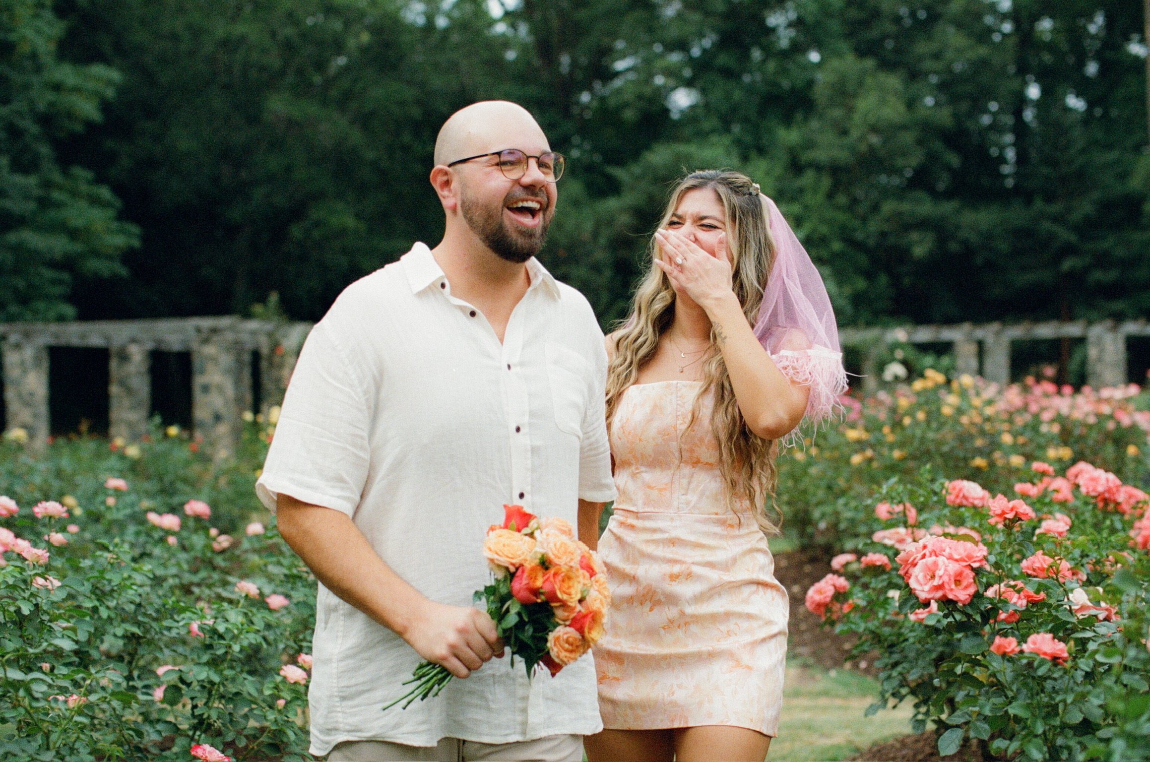 Ian laughing with the bouquet as Nicole covers her mouth mid-laugh beside him.