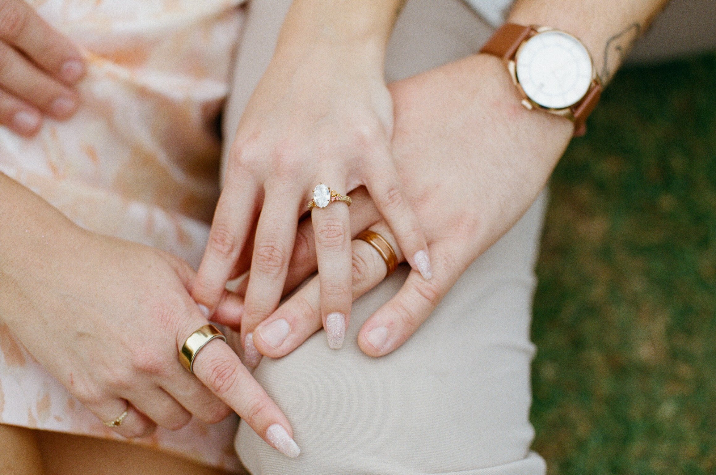 Close up: Nicole’s and Ian’s hands together, her engagement ring and his gold band.